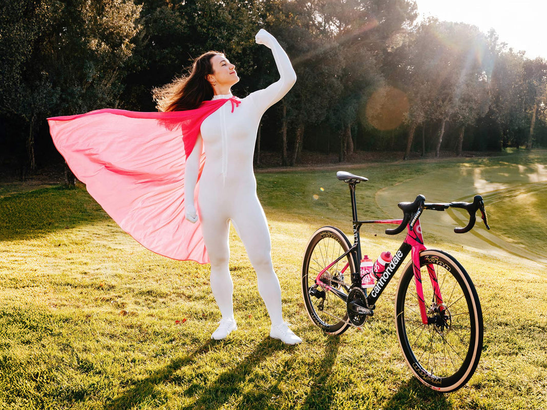 Rider with a pink cape beside a Cannondale SuperSix EVO